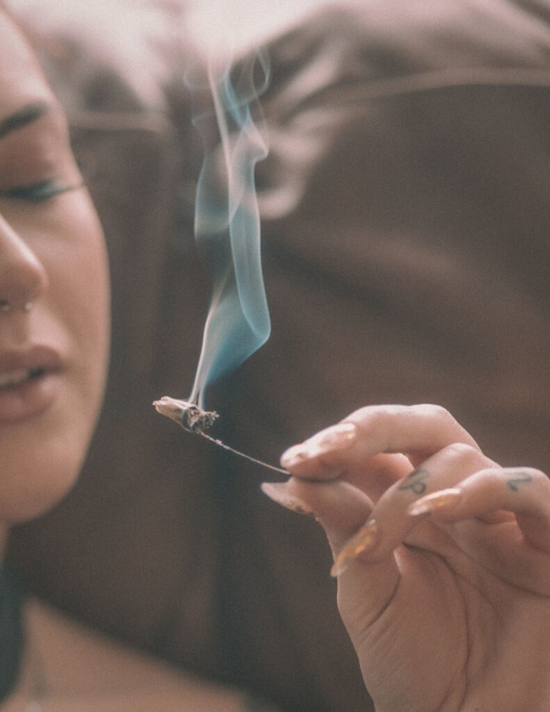 A close-up of a member of Randy’s community holding a partially smoked roll with a visible support wire. Delicate smoke rises in the air, creating a relaxed and mindful atmosphere that represents Randy’s lifestyle.