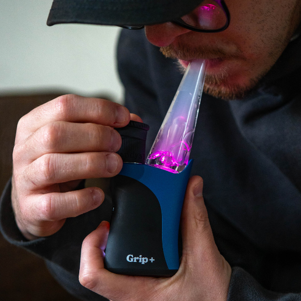 Person using a Randy’s Grip+ concentrate vaporizer with a glowing pink LED bubbler attachment.